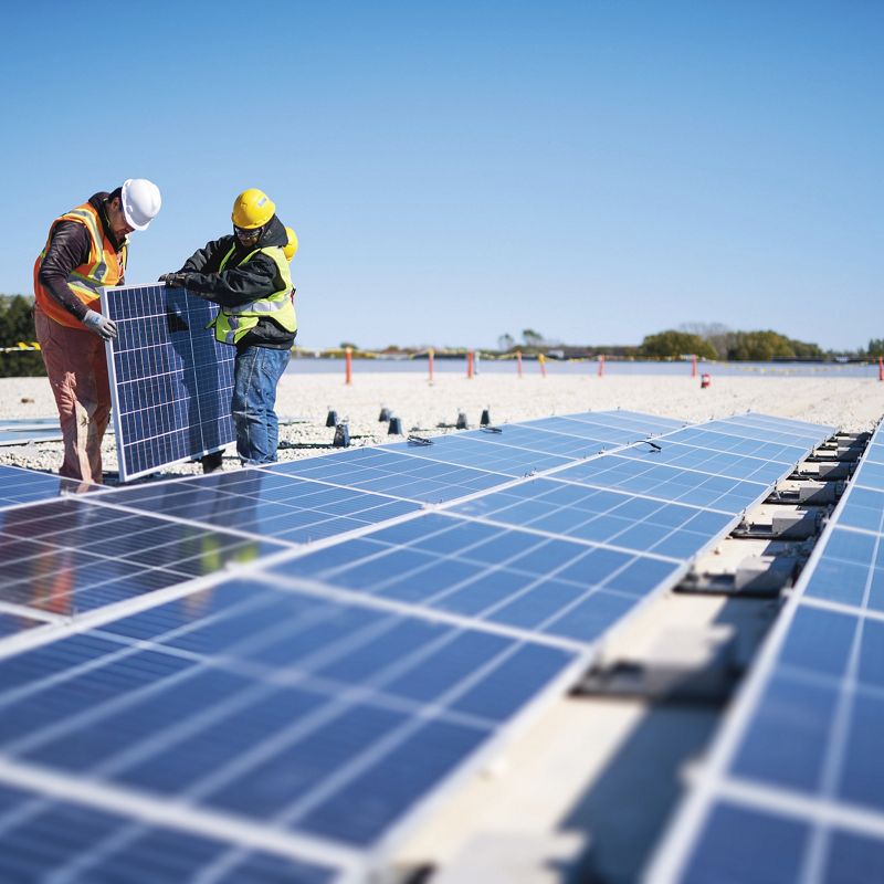 Workers set up solar panels.