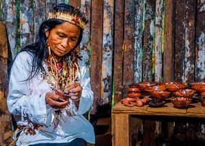 A woman in her traditional attire handles pottery crafts with a smile.