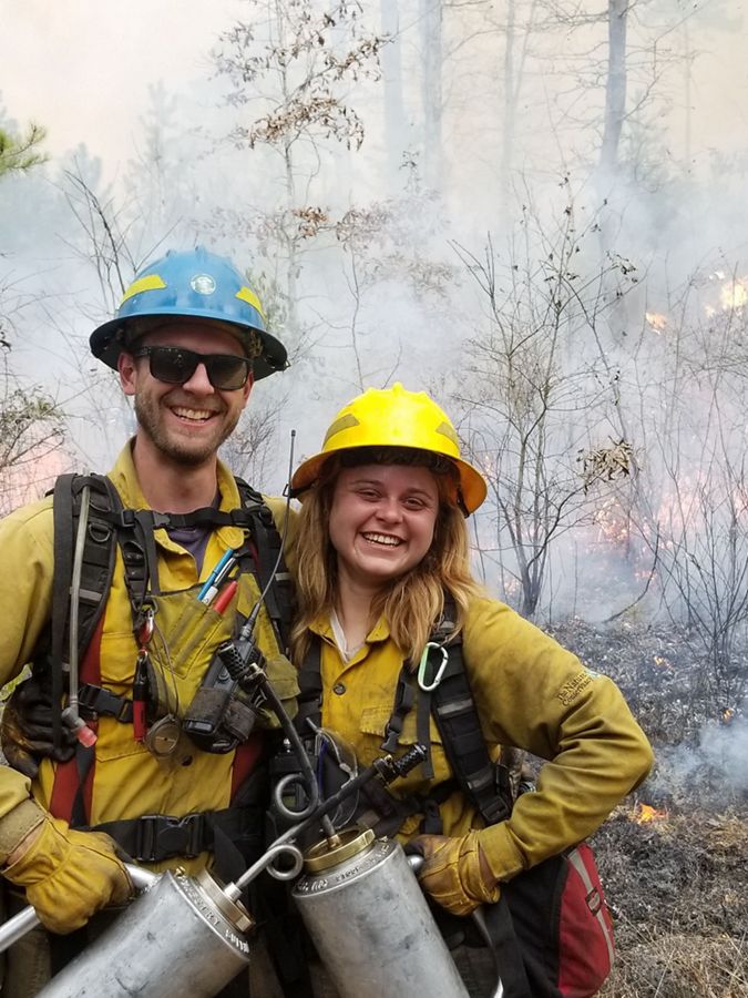 Two people pose in fire gear. 