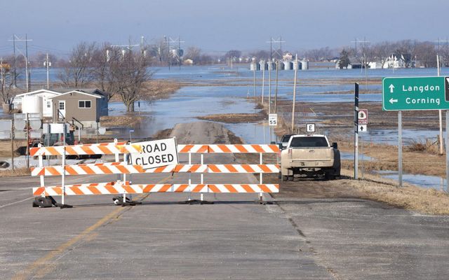 A road-closed barricade blocks traffic from entering flooded areas. 