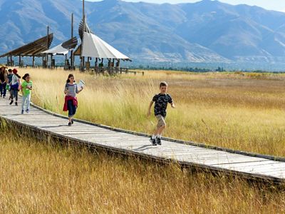 A group of kids running on a boardwalk.