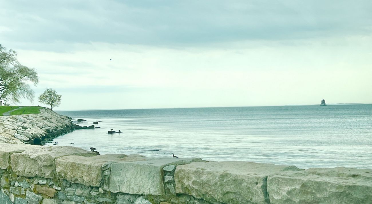A stone wall frames calm ocean waters.