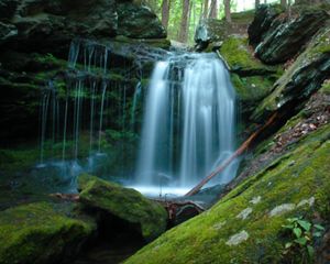 A waterfall pours over large rocks.