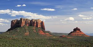 A wide, landscape view of a red rock formation with a blue sky above. 
