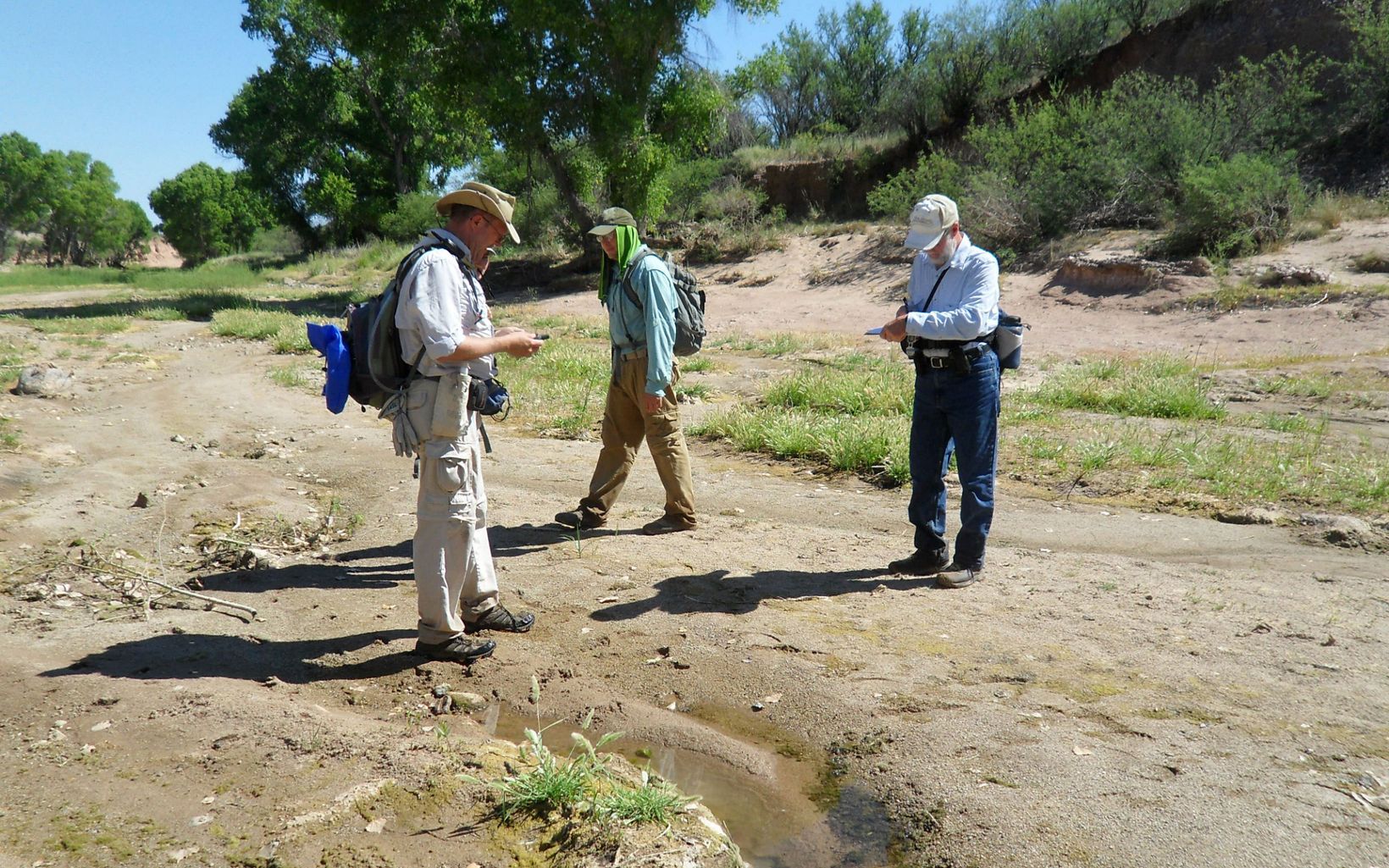 Mapping volunteers stand on a dirt path and hold GPS technology.