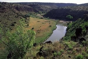 Landscape of a canyon with lush vegetation and a river running in the middle.