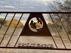 View of a metal gate with the TNC logo and the words Shield Ranch.