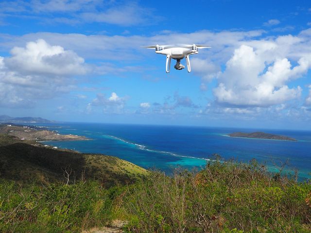 an aerial drone flies over a coastal area with blue sky and ocean in background
