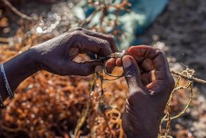 A closeup image of a pair of hands tying a rope in a knot.