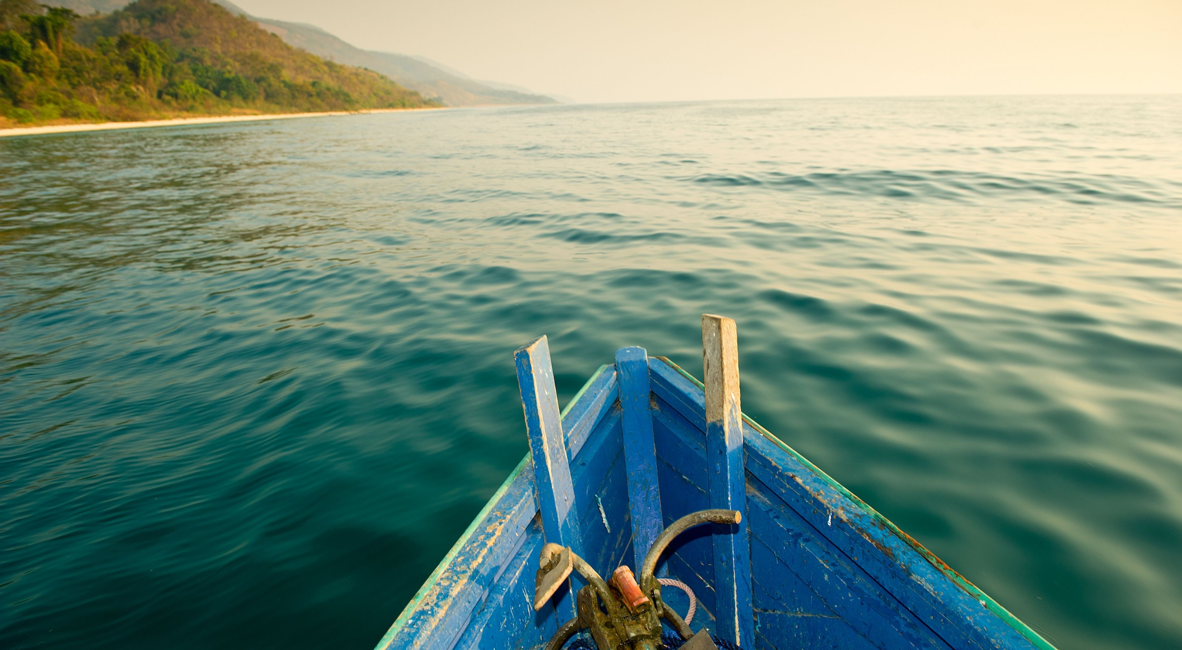 The front of a small, blue boat over the waters of Lake Tanganyika.