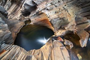 An aerial view showing a body of crystal-like water wedged within an ancient rock formation