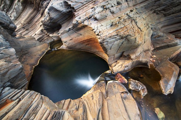 An aerial view showing a body of crystal-like water wedged within an ancient rock formation