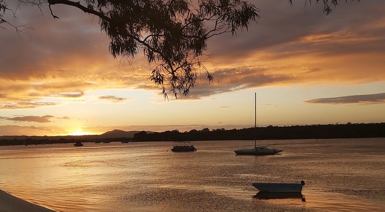 Sunset showing orange skys over the waterway with boats in the background.