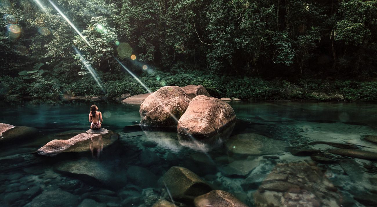 a woman sitting on rocks surrounded by water
