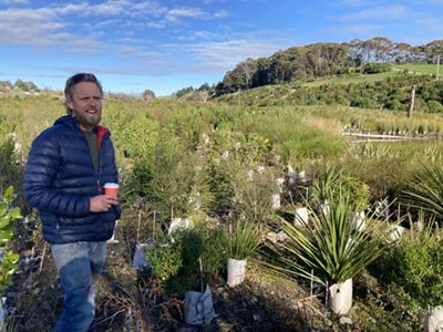 A man stands next to plantings of native plants.