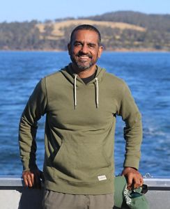 Raymond de Silva smiling standing against a boat railing.