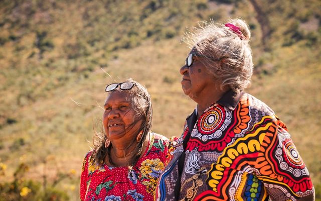 two indigenous women in colorful dresses.