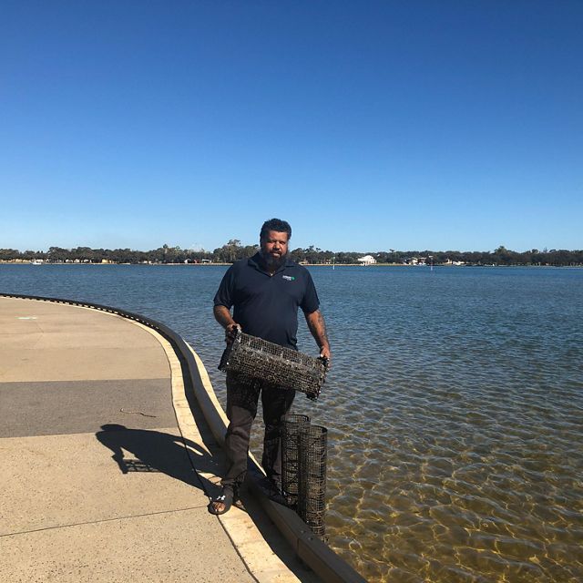 Man holding mussel baskets near estuary