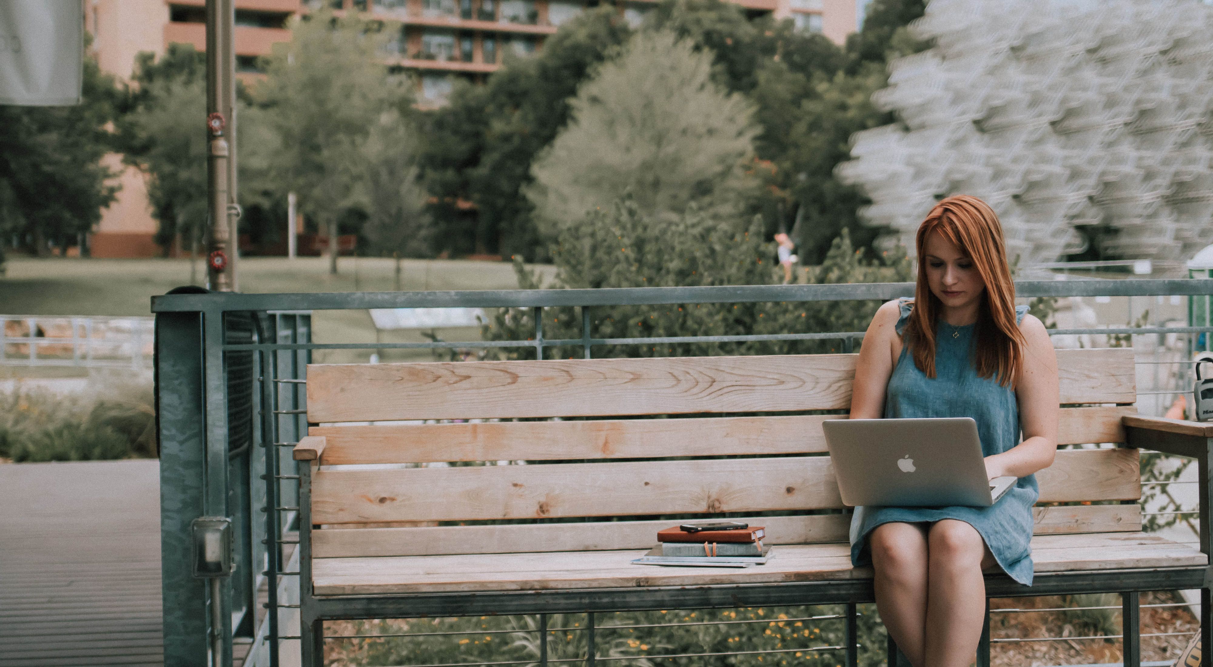 woman sitting on a city park bench with a laptop
