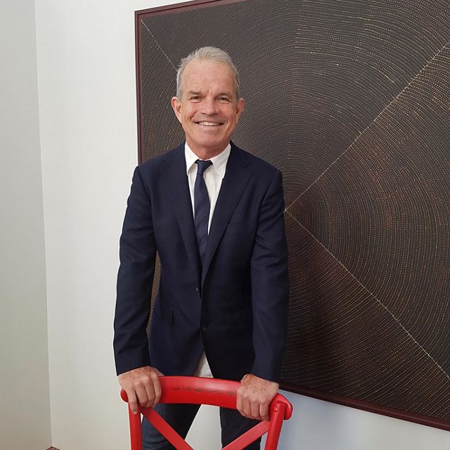 man in a suit leaning on a red chair
