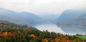 Landscape view of a lake amidst mountains shrouded in mist.