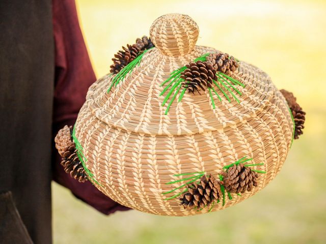 A brown woven basket adorned with bright green raffia and pinecones.