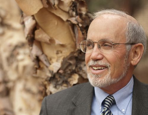 A man wearing glasses smiles poses for a picture.