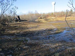 A muddy field with a water tower in the background.