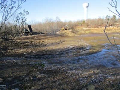A muddy field with a water tower in the background.