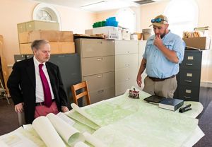 Two men looking at a table full of maps.