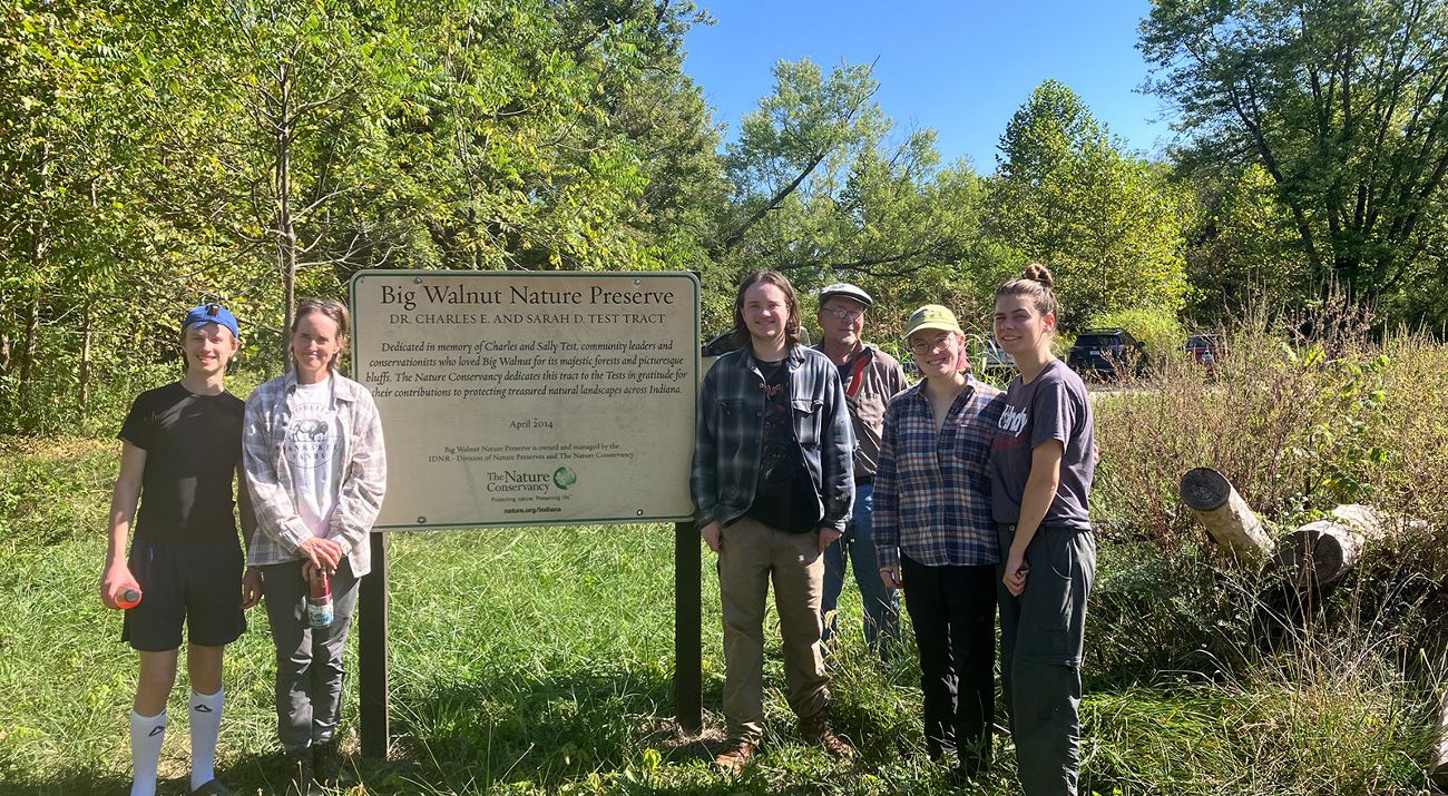 Six people stand next to Big Walnut Nature Preserve wood-routed sign.