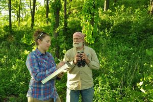 At Baraboo Hills, Ann Calhoun stands, taking notes on a clipboard, as Mike Mossman talks with her, holding binoculars.