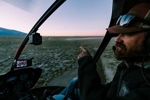 A man in a helicopter monitoring bison herds.