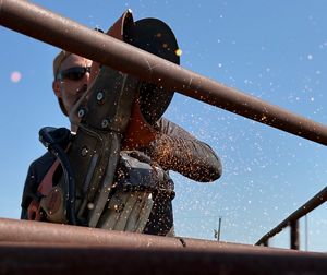 Sparks fly as a TNC employee uses tools to cut through metal of the bison corral. 