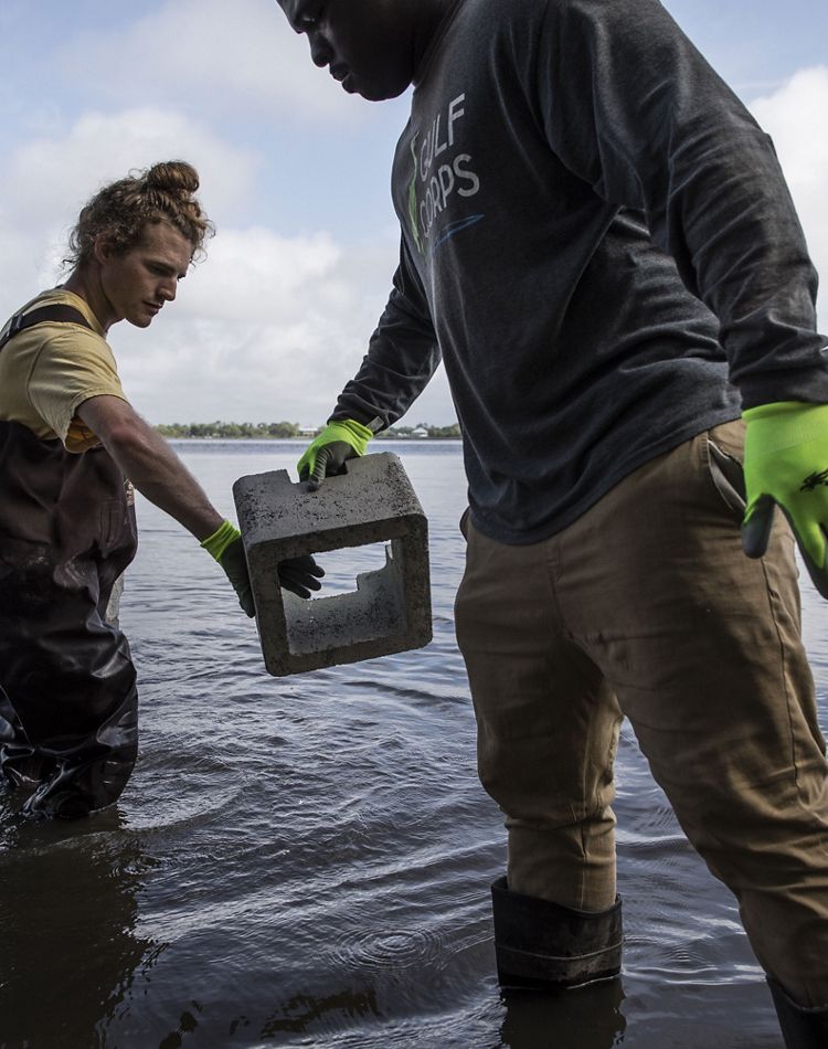 One crew member passes a concrete block to another.