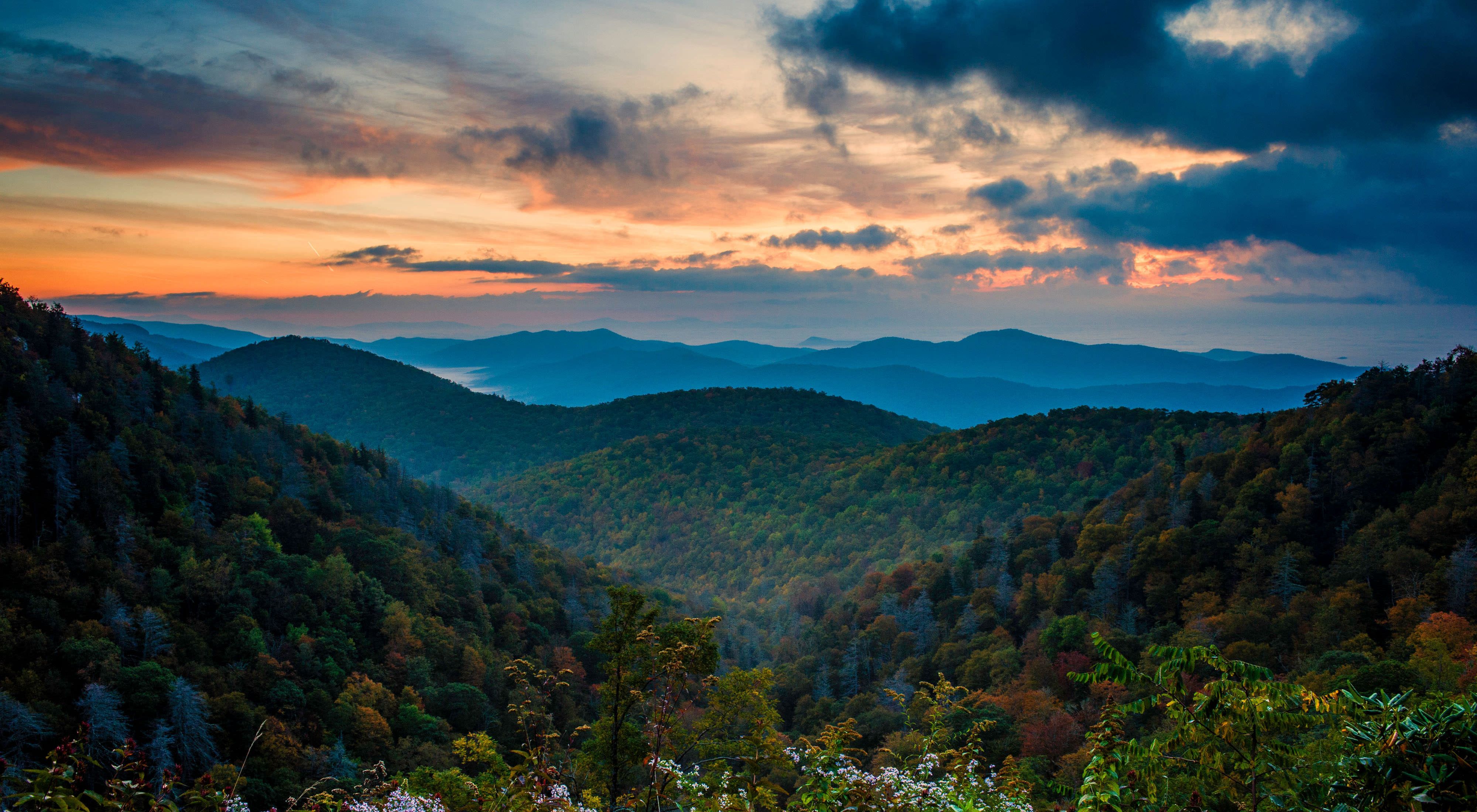 Dramatic panoramic view of forested mountains at sunset.