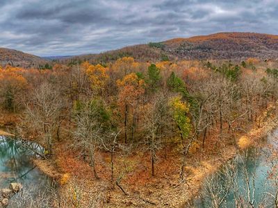 An aerial view of a river running through a forested area in the fall.