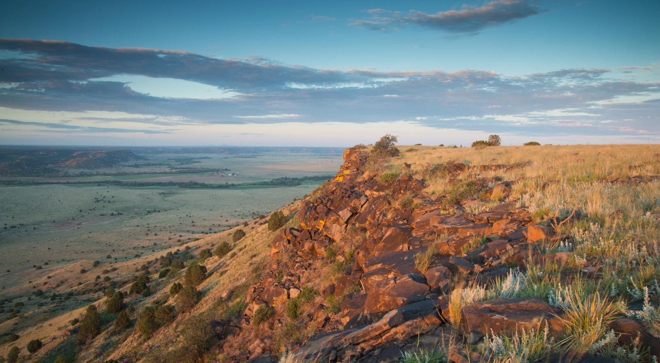 Looking down from the top of the mesa across a vast expanse of green valley.