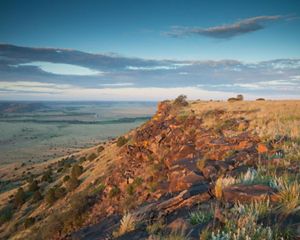Looking down from the top of the mesa across a vast expanse of green valley.