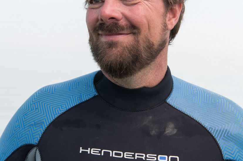 Portrait of a smiling man wearing a blue and black wetsuit. 