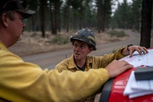 Two firefighters having a conversation about wildfire impact.