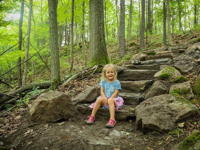 A girl sitting on the steps of a new trailhead.