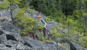A woman sits among stones on a mountain talus slope.