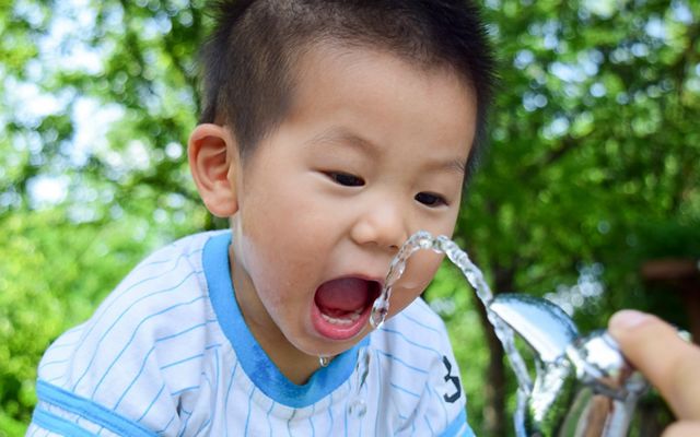 A boy drinks water out of a fountain.