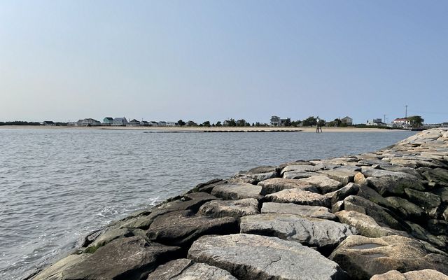 A rock wall wraps around a calm body of water along a coast. 