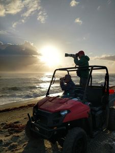 Two volunteers on an ATV at dusk use optical gear to view the beach at dawn.