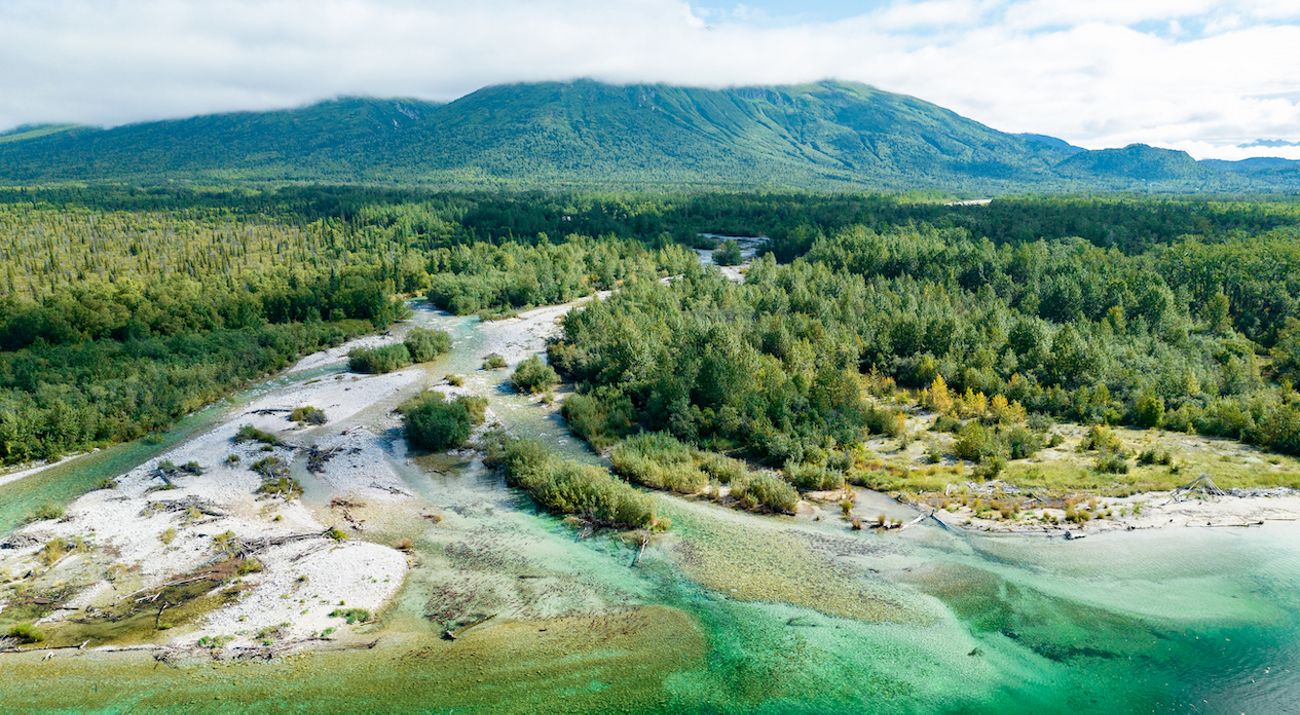 Aerial view of clearwater lake in Alaska's Bristol Bay with a mountain in the background.