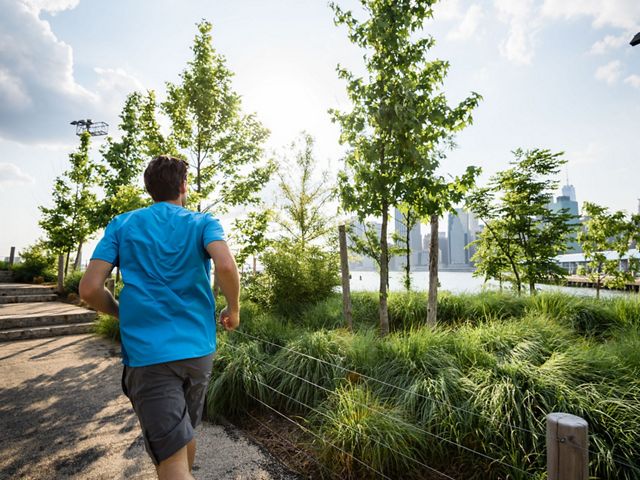 Man running through park with view of Manhattan skyline