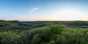 Green, forested hills stretch to the horizon under a blue sky.
