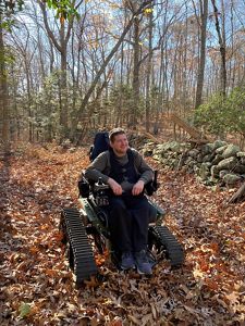 A man sits in a wheelchair tailored for the outdoors.